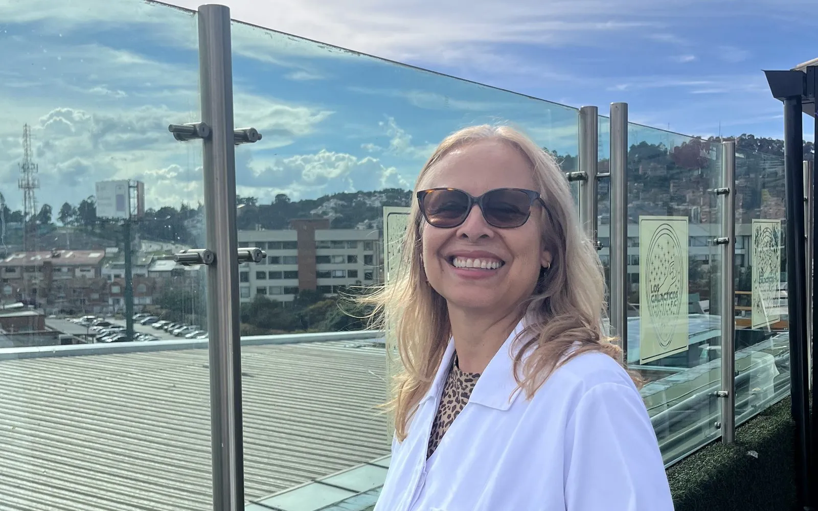 Dra. Ana Belén España, de Óptica Apolo, sonriendo con gafas de sol en un balcón del Centro Comercial Bulevar Niza, Bogotá