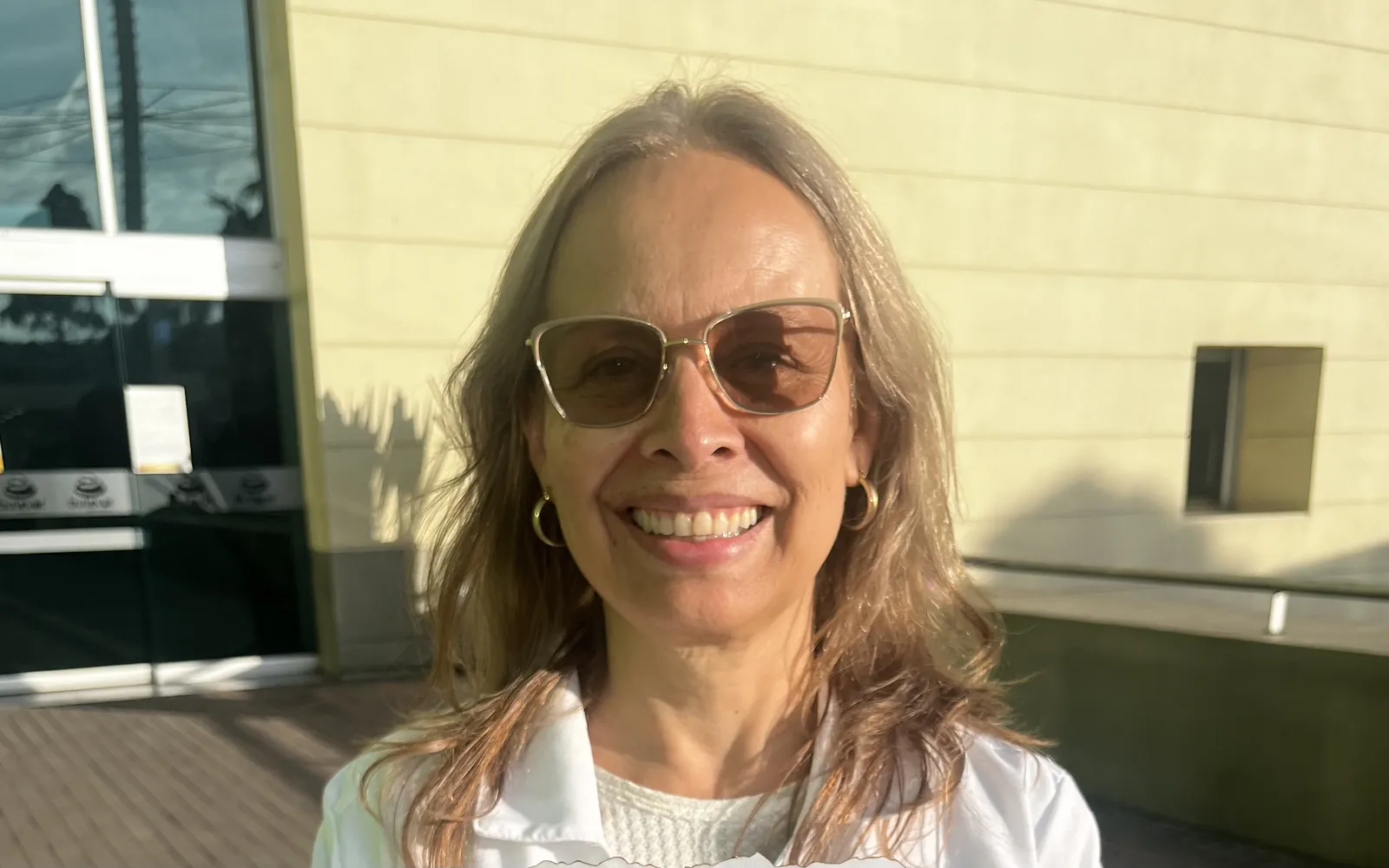 Dra. Ana Belén España, optómetra de Óptica Apolo, sonriendo al aire libre con lentes fotosensibles oscurecidos por el sol